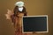 Woman showing blank blackboard isolated on beige background