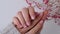 Woman showing hands with beautiful nude manicure holding delicate pink Gypsophila or baby's breath flowers. Female