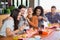 Woman showing mobile to cheerful friends in restaurant