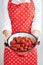 Woman showing strawberry in colander