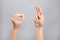 Woman showing word okay on grey background. Sign language