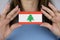 A woman shows a business card with an image of the Lebanon flag