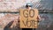 Woman shows cardboard with Go Vote sign on brick wall urban background. Honest political voting concept. Use your voice