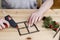 Woman shows how to make miniature wooden window frame decorated with holly (ilex), fir and cones