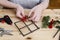 Woman shows how to make miniature wooden window frame decorated with holly (ilex), fir and cones