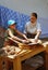 A woman shows to a girl how to wash clothes using vintage tools.