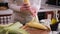 woman shucking shell hull fresh corn cob in her kitchen