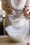 Woman sieving flour into a bowl