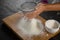 Woman sieving flour from the bowl on the wooden board