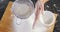 Woman sieving flour from the bowl on the wooden board 4k