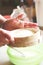 Woman sifting flour for yeast dough in kitchen