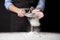 Woman sifting wheat flour at table against black, closeup