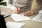 Woman signing document, focus on female hand putting signature,