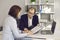 Woman signs contract sitting at desk in bank manager or insurance agent's office