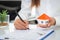 A woman signs a contract to purchase a home with a real estate agent. Model house with keys on table