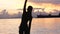 Woman silhouette doing exercise at the beach with clouds and vibrant sunrise.