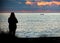 Woman in silhouette observes the sea and the boat in the sunset lights. I imagine it is the fisherman`s wife who is awaiting her