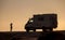 Woman silhouette is posing  for photographer in front of offroad motorhome truck in the evening sunlight