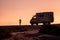 Woman silhouette is posing  for photographer in front of offroad motorhome truck in the evening sunlight