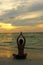 Woman silhouette practicing yoga on the beach