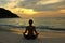 Woman silhouette practicing yoga on the beach