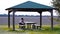 Woman silhouette sits on wooden bench at table under tent