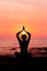 Woman silhouette sitting in lotus position on sea background back lit