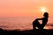 Woman silhouette sitting on sea background back lit