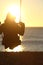 Woman silhouette swinging at sunset on the beach