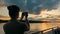 Woman silhouette taking photo of sunset with smartphone on deck of cruise ship