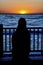 Woman silhouetted against ocean and orange sky in San Diego California sunset