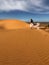 Woman in silk wedding dress with fantastic view of Sahara desert sand dunes