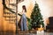 A woman in a silver long dress in a room decorated with a spiral staircase decorated for Christmas