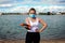 Woman in singular mask do exercises on the beach