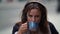 Woman is sipping hot coffee from cup in street cafe, closeup portrait in slow motion, using headphones for listening to