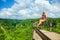 Woman sit at balcony on high cliff with jungle view