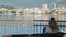 Woman sit bench city sea bay skyline back view Rapallo Italian Riviera Italy