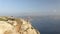 Woman sit and eat lunch on large steep rocky cliff edge