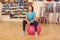 Woman sit on a pink Pilates ball indoors gym background.