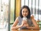 Woman sits in coffee cafe wirh iced coffee on table.