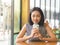 Woman sits in coffee cafe wirh iced coffee on table.