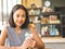 Woman sits in coffee cafe wirh iced coffee on table.