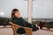 Woman sits in a cozy wicker chair on a light covered veranda in the mountains, enjoys relaxing, smiling, stretching out her legs