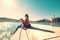 Woman sits with dog on wooden sea pier at sunny windy day