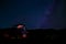 A woman sits in a farmer`s automobile, gazing at the stars in the night sky, with the Milky Way in the background