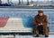 A woman sits in a fur coat on a pier in the port of Baku - AZERBAIJAN