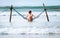 Woman sits in hammock swing over ocean surf line - island summer