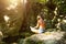 A woman sits in a lotus field on a large rock among the rocks in the open air and meditates, enjoys the unity with nature, listens