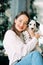 Woman sits near Christmas tree and plays with puppy of dalmatian dog