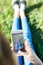 A woman sits in a park on the grass with a phone in hands